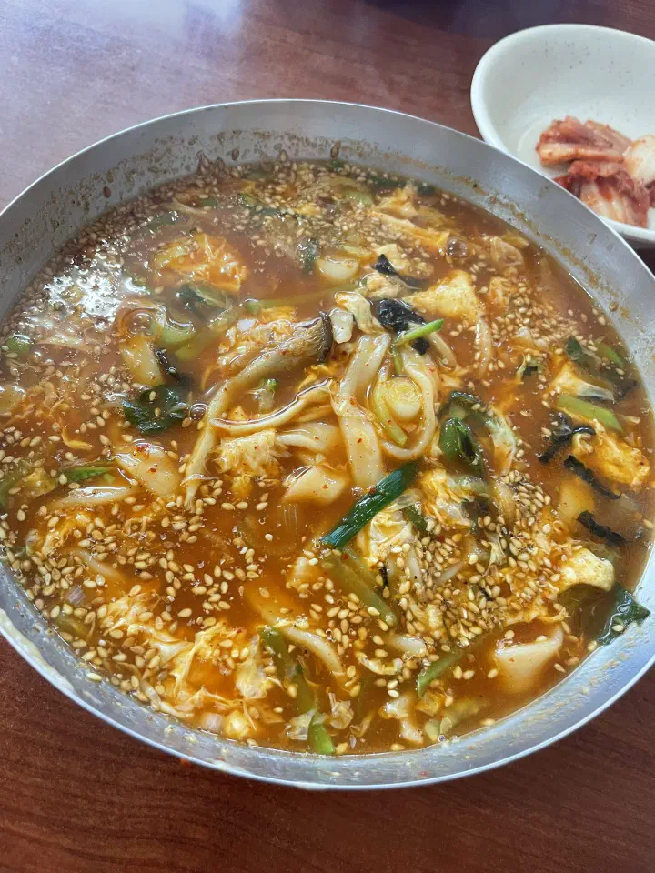 Bowl of Geumcheon Kalguksu jang kalguksu served with a side of cabbage kimchi