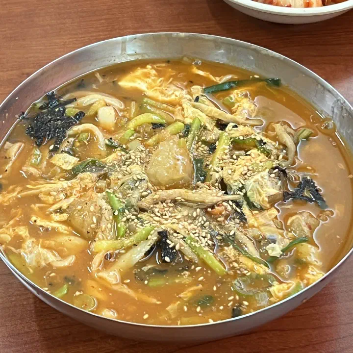 Overhead view of a bowl of jang kalguksu ongsimi at Geumcheon Kalguksu