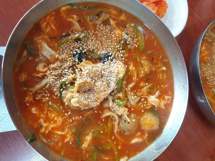 Close-up of the red gochujang broth of jang kalguksu covered in toasted sesame seeds
