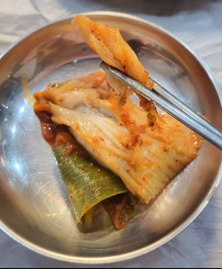 앞접시에 덜어 놓은 가오리찜 무와 살, 젓가락으로 무를 집고 있다