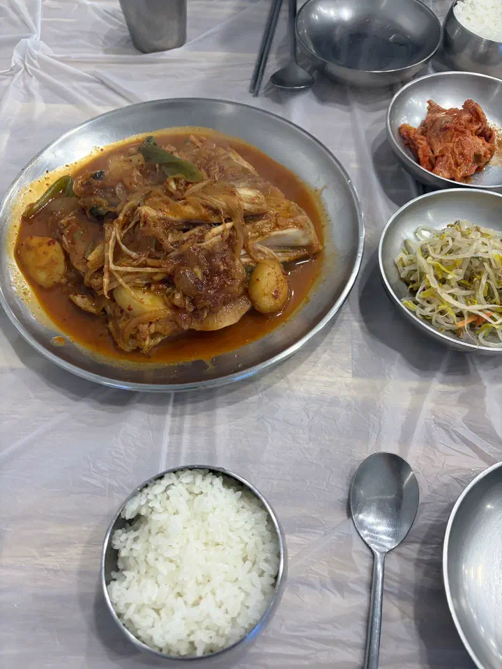 A small portion of braised skate served with a bowl of rice and side dishes for one person