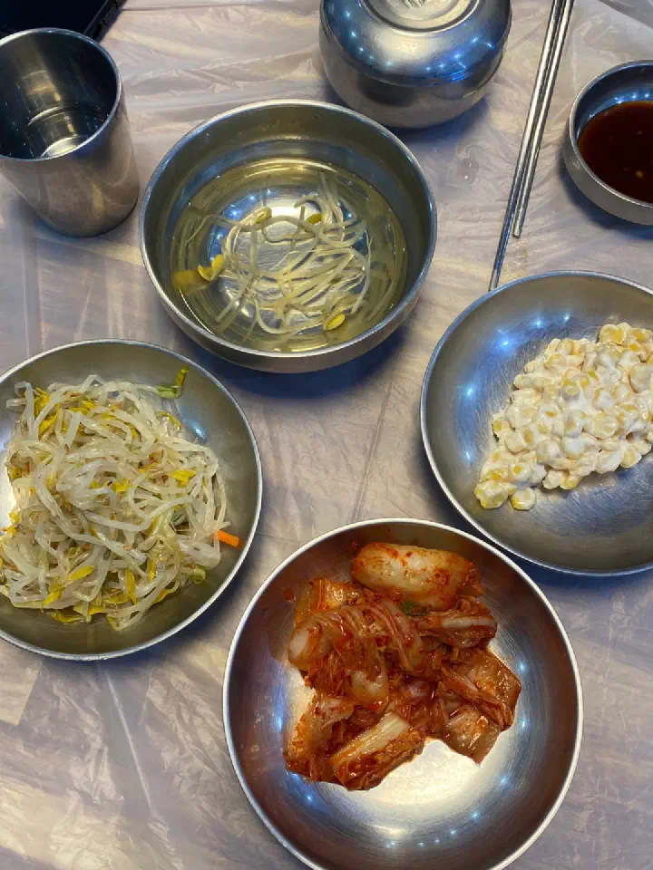 The four side dishes at Goseong Saengseonjjim: bean sprouts, kimchi, corn salad and bean sprout soup