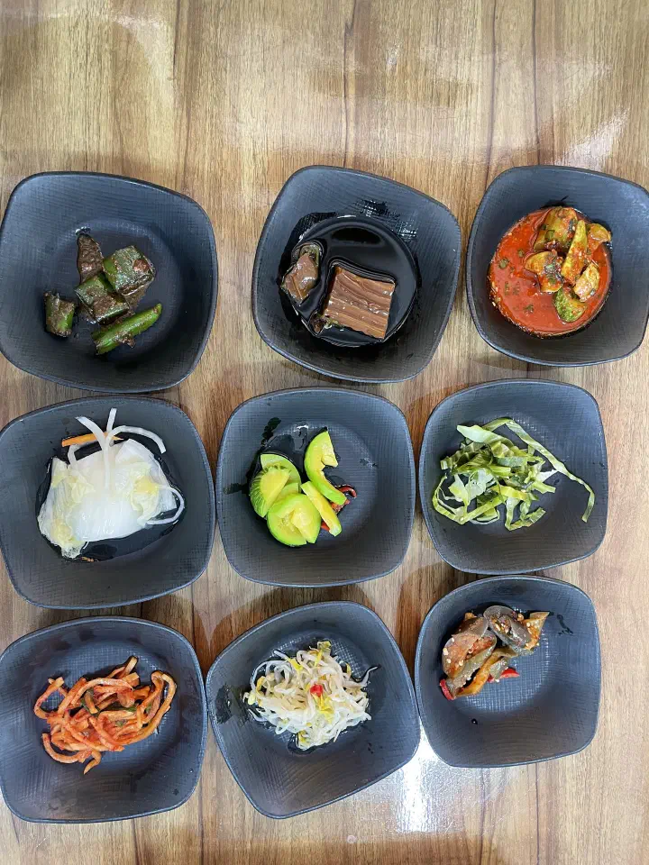 Nine small banchan side dishes served with the meal at Gunammae Dubujip