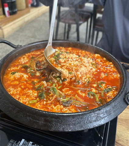 Ladle scooping the soft tofu and broth of sundubu jeongol at Gunammae Dubujip