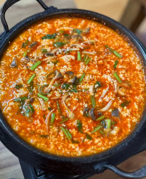 Bubbling pot of sundubu jeongol full of soft tofu curds at Gunammae Dubujip