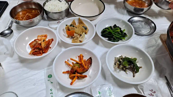 Banchan side dishes at Jeonghwa Sikdang: kimchi, fish cake, spinach, radish salad and anchovies with peppers