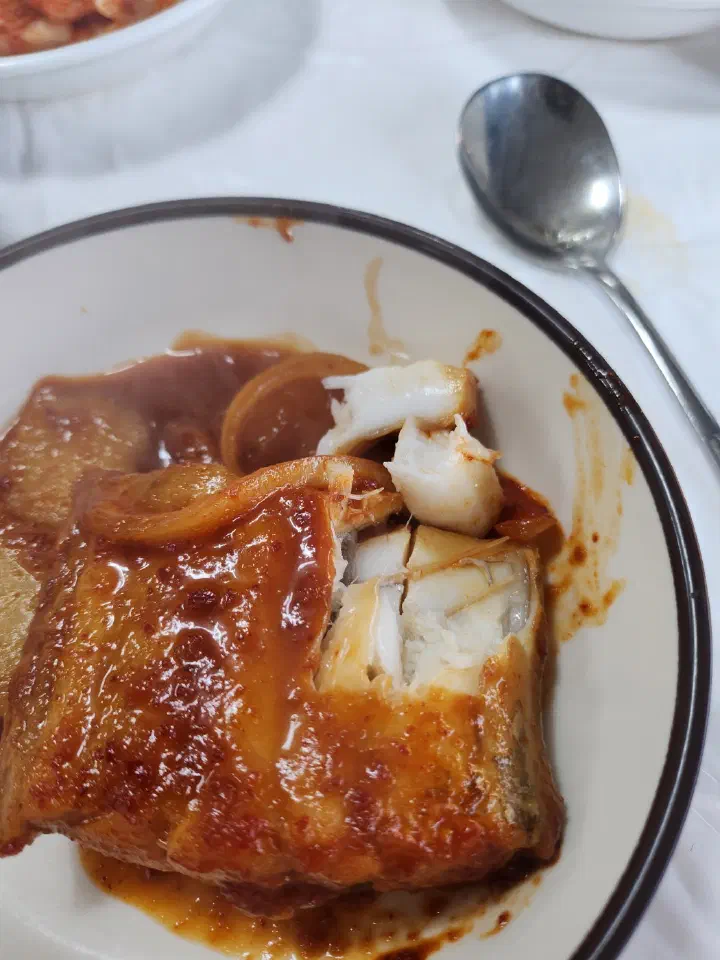 White flakes of hairtail lifted onto a small plate with braised radish