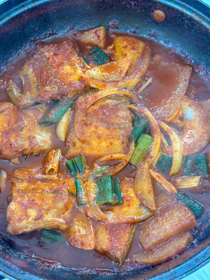 Close-up of thick cross-cut hairtail pieces braised in a shallow red sauce