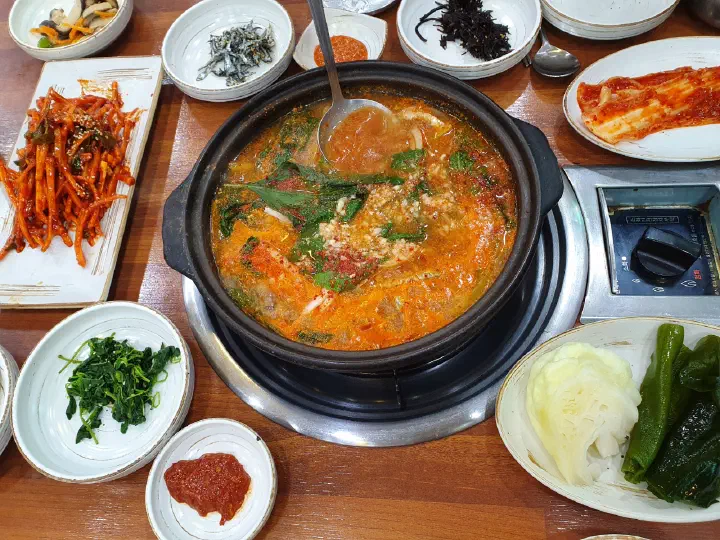 Full Geoje Myeolchi Ssambap set table with anchovy stew, side dishes, wrap vegetables, and raw anchovy salad