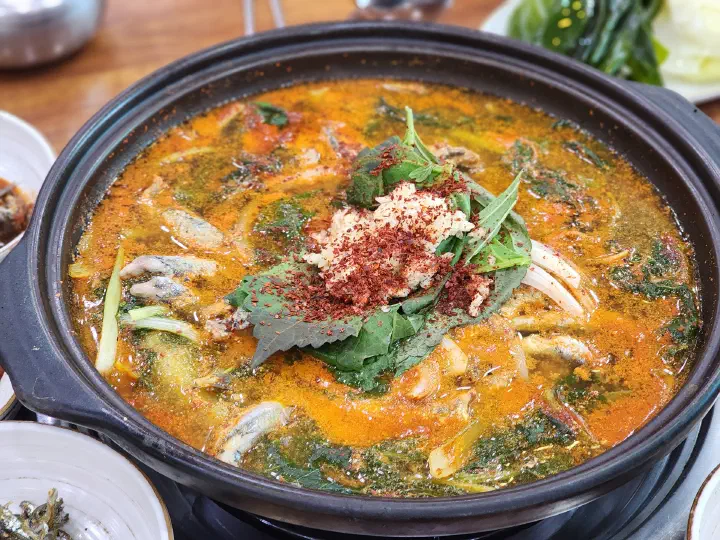 Close-up of whole anchovies in the Geoje stew, each one head-to-tail and finger-length