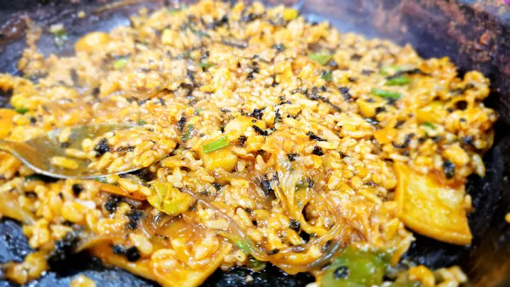 Close-up of fried rice crisping into a scorched nurungji layer at the bottom of the pot