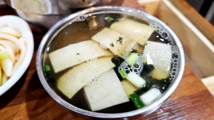 Bowl of clear eomuk fish cake broth with green onion and seaweed