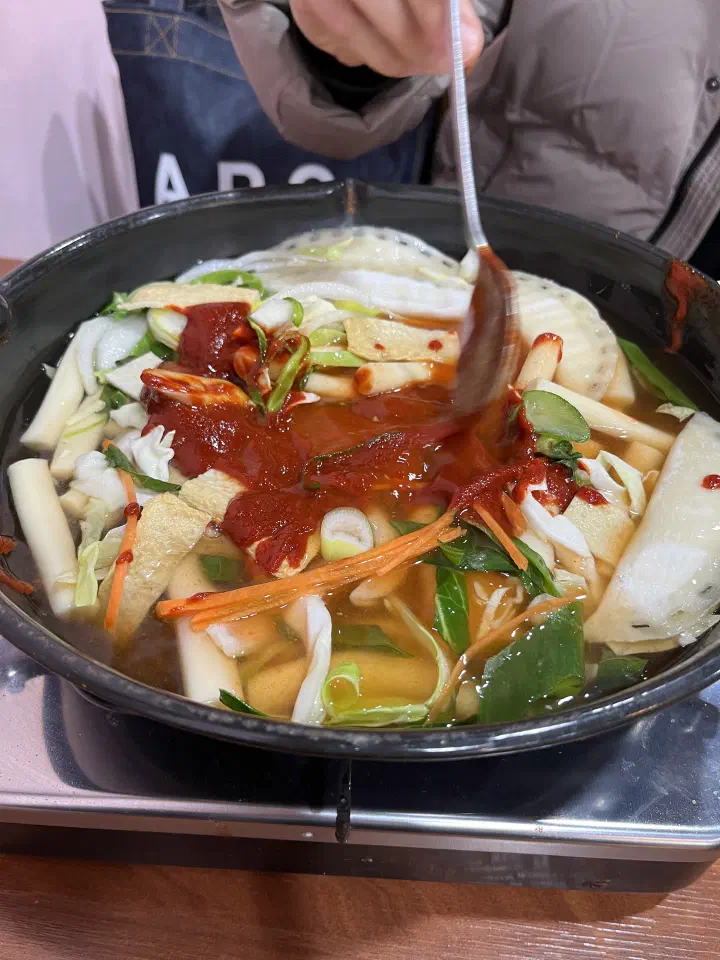 Raw rice cakes, fish cake and cabbage topped with gochujang sauce before simmering