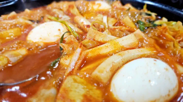 Close-up of tteokbokki sauce thickened around two boiled eggs