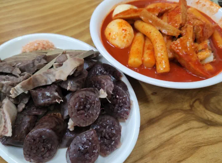 A plate of sundae blood sausage served alongside tteokbokki, a classic Korean bunsik spread
