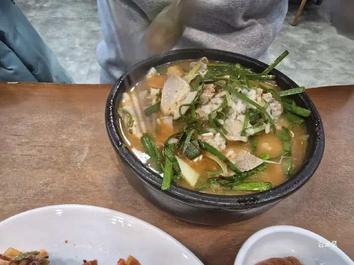 A bowl of Miryang Dwaeji Gukbap&rsquo;s clear, light pork rice soup served with the rice already mixed in