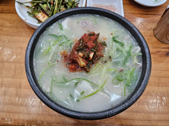 Top-down view of dwaeji gukbap piled high with shredded scallion at Miryang Dwaeji Gukbap