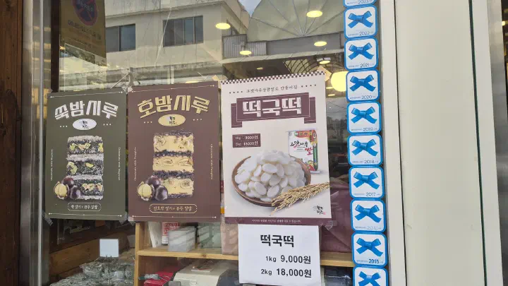 부자떡집 유리창에 붙은 블루리본 스티커와 쑥밤시루 호밤시루 안내 포스터