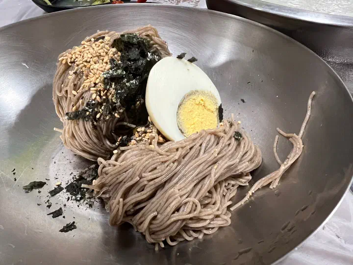 Close-up of thin Baekchon Makguksu buckwheat noodles topped with laver and boiled egg