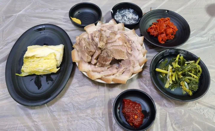 Baekchon Makguksu pyeonyuk plate with white kimchi and seasoned pollack sides