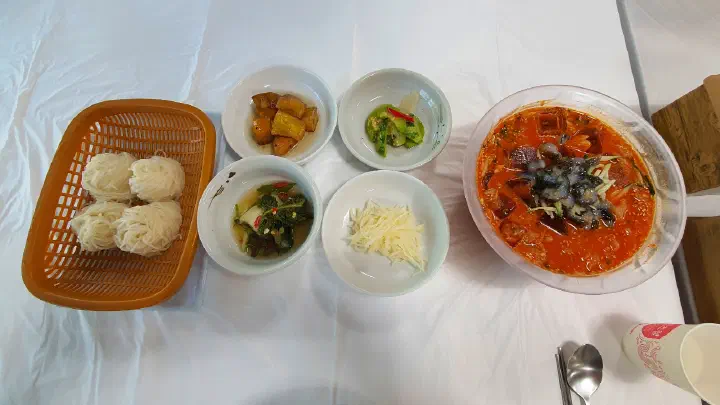 Korean side dishes including candied sweet potato and seasoned greens served with mulhoe at Gwangbeomine Hoetjip