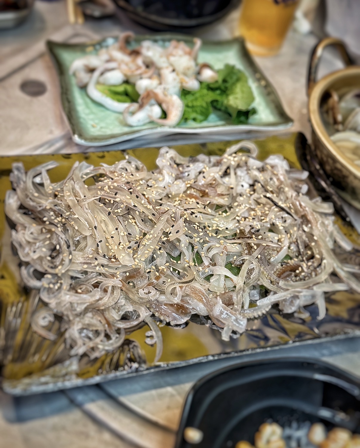 Live squid sashimi sliced into long ribbons on a plate