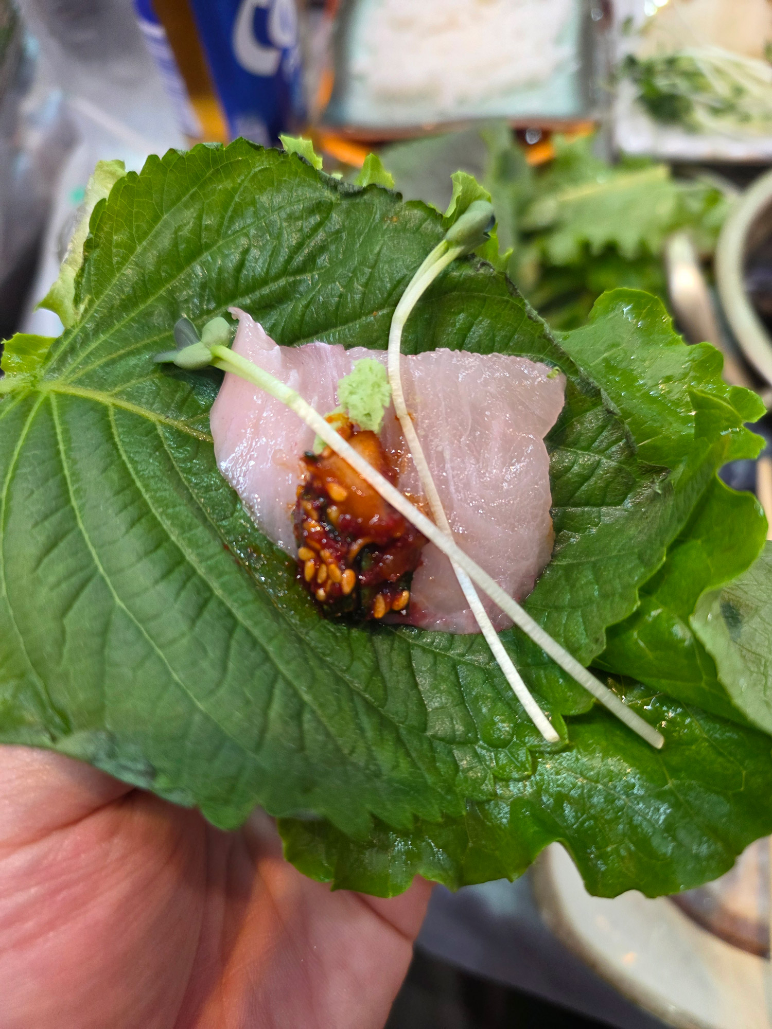 A bite of sashimi wrapped in a perilla leaf