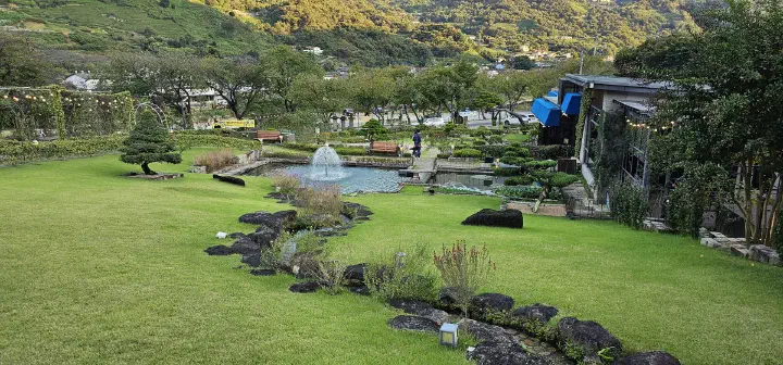 Lawn, fountain, pond, and pine bonsai in the garden at The Road 101 cafe