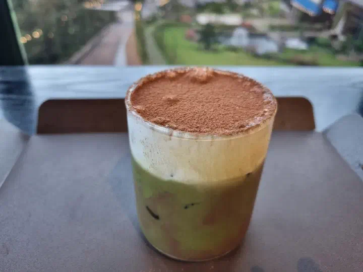 Close-up of The Road 101 green tea cream latte dusted with cocoa powder