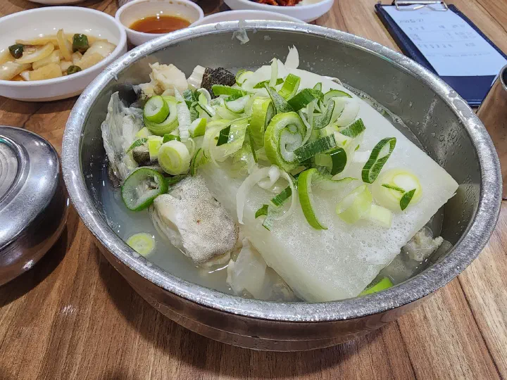 A bowl of Haeundae Giwajip Daegutang clear cod soup with a big radish chunk and cod in clear broth