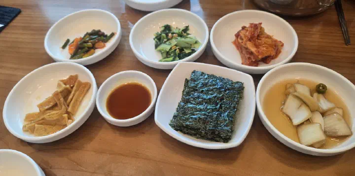 Korean side dishes at Haeundae Giwajip Daegutang including roasted seaweed, kimchi, and pickled onion