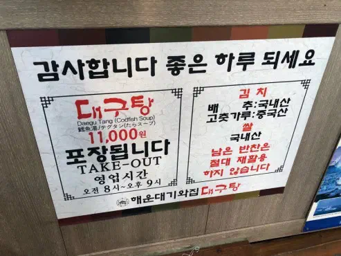 Notice board at Haeundae Giwajip Daegutang showing cod soup price, takeout, hours, and ingredient origins