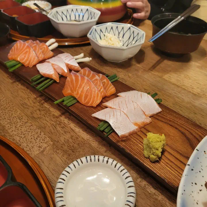 Salmon sashimi platter neatly arranged on a wooden board at Haemok