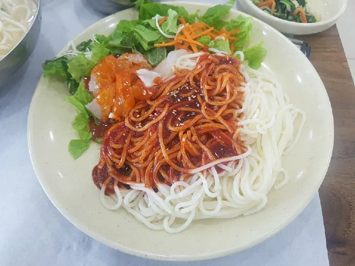 Chonchon Haenyeochon hoe-guksu before mixing it by hand with the plastic glove