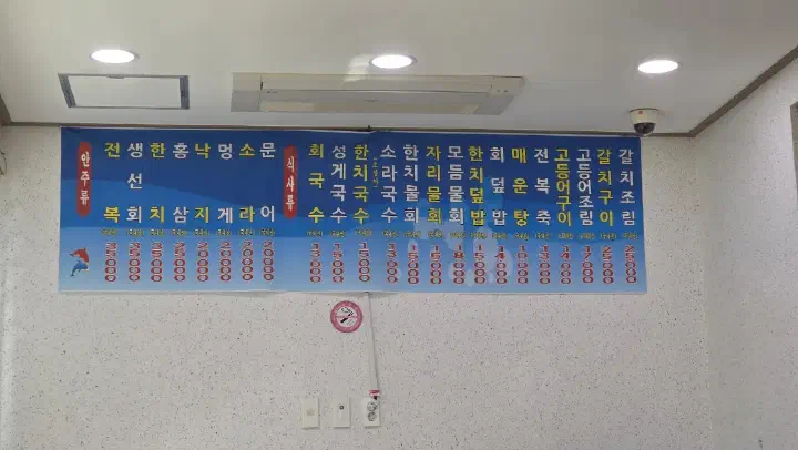 Menu board with prices on the wall at Chonchon Haenyeochon in Jeju