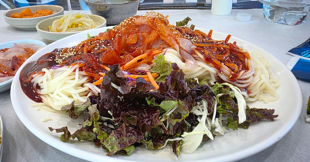 Hoe-guksu by the ocean-view window at Chonchon Haenyeochon, Jeju