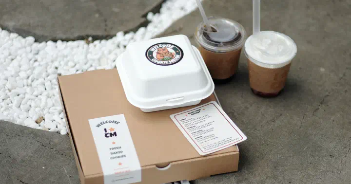 Cookiemeow takeout cookie box with a cat-logo sticker next to two iced drinks