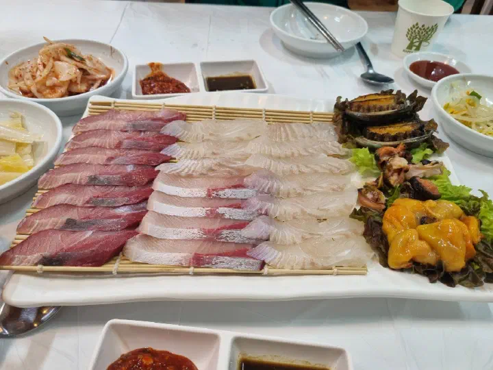 Assorted sashimi platter at Gommak Sikdang with amberjack and white-fish sashimi served alongside abalone, sea squirt and conch