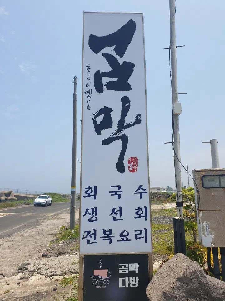 구좌해안로 도로변에 선 곰막식당 입간판, 회국수·생선회·전복요리 안내