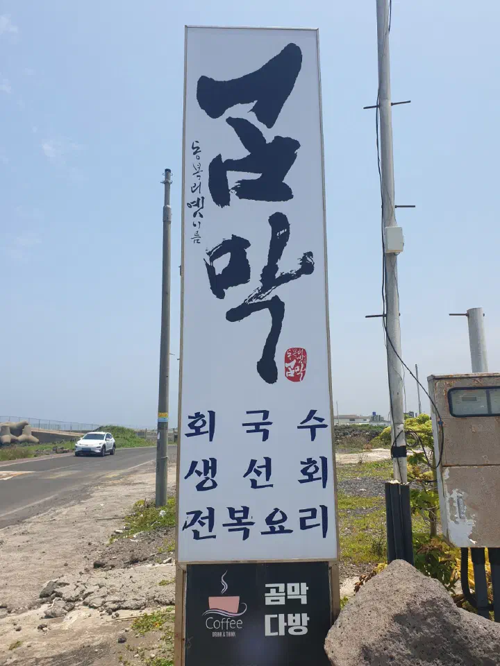 Roadside sign for Gommak Sikdang along Gujwahaean-ro, listing raw fish noodles, sashimi and abalone dishes