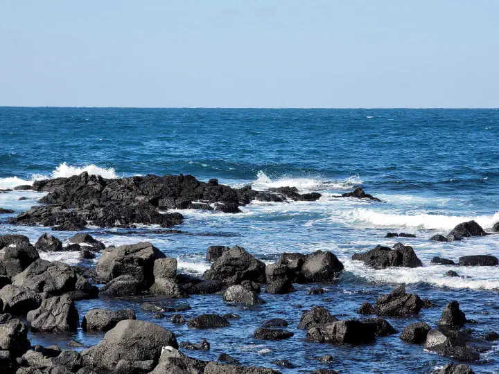 Black volcanic rocks and the blue Jeju sea along the Gujwa coast in front of Gommak Sikdang