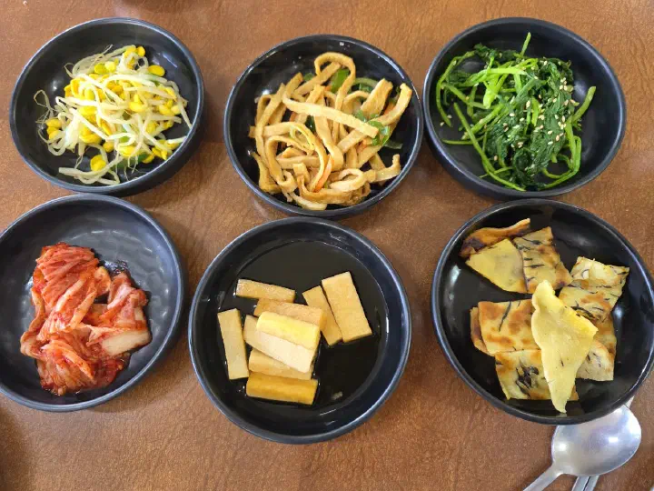 Six Korean banchan side dishes served at Sogeumbachi Sooninae, including bean sprouts, seasoned greens, and kimchi