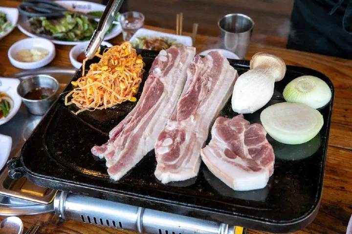불판에 구워지는 제주 흑돼지 오겹살과 콩나물