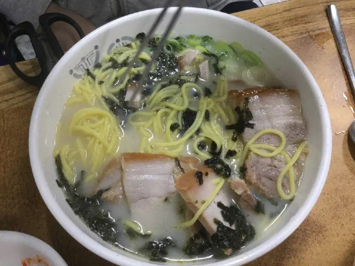 Top-down view of Jamae Guksu gogi-guksu with several slices of pork and dried seaweed