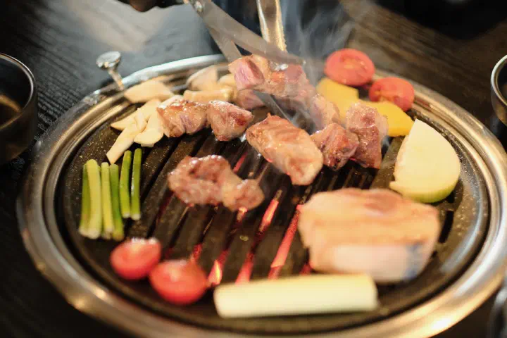 Pineapple, green onion, and cherry tomato grilling alongside Jeju black pork