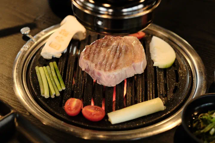 Grill marks forming on a thick cut of Jeju black pork neck