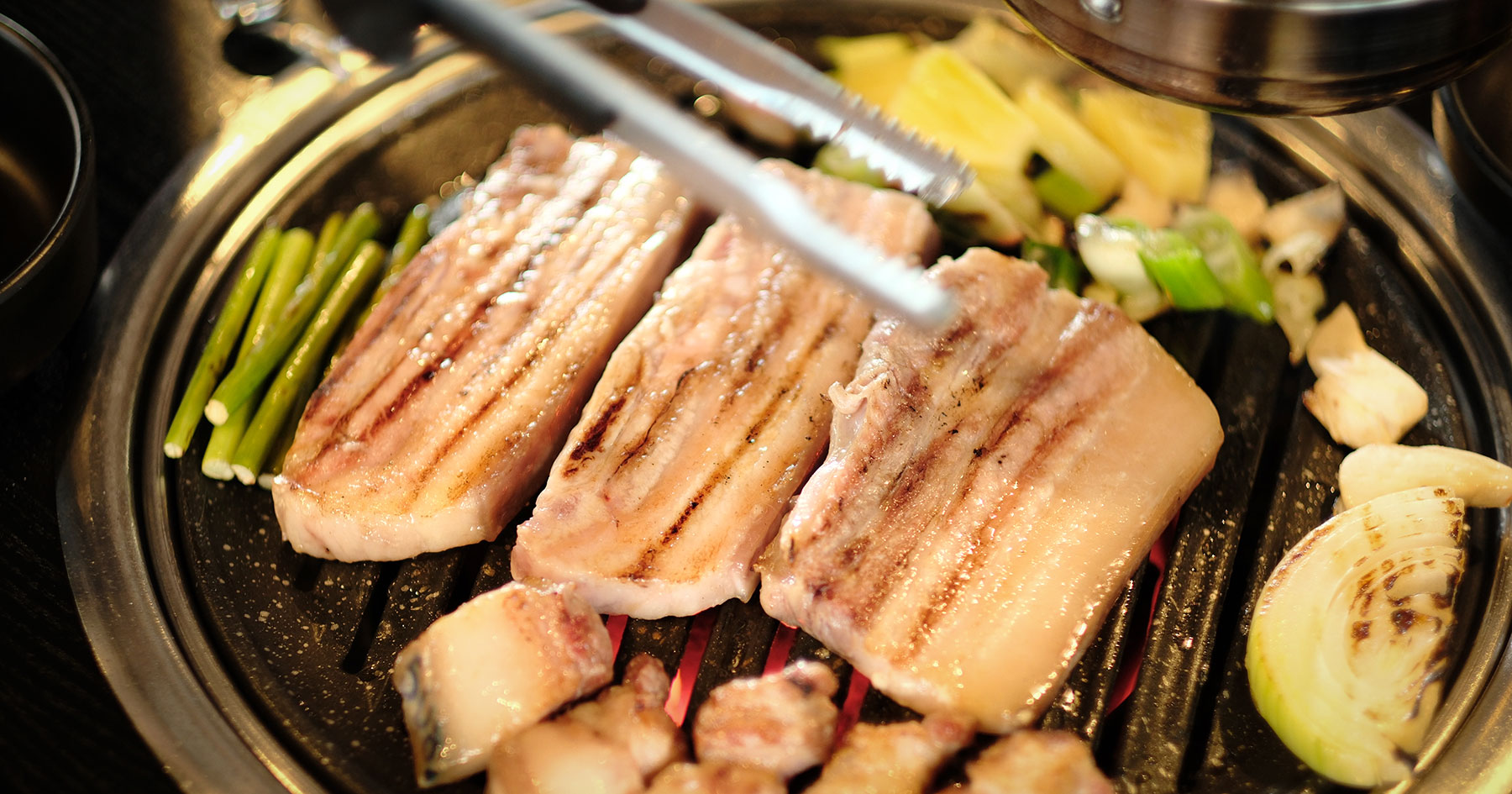 Thick-cut Jeju black pork on the grill at Udam in Jungmun
