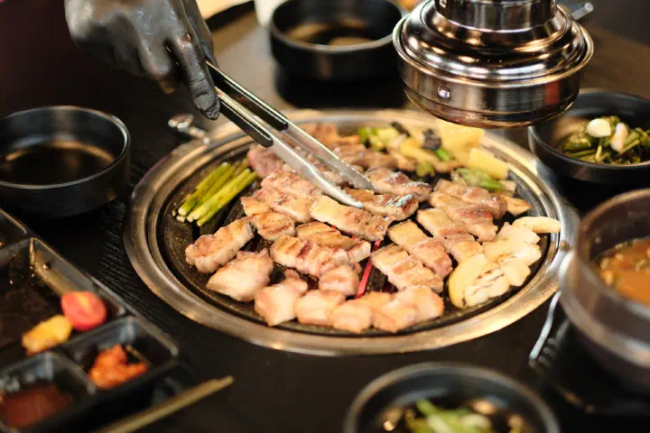 A charcoal grill full of golden-browned Jeju black pork at Udam in Jungmun