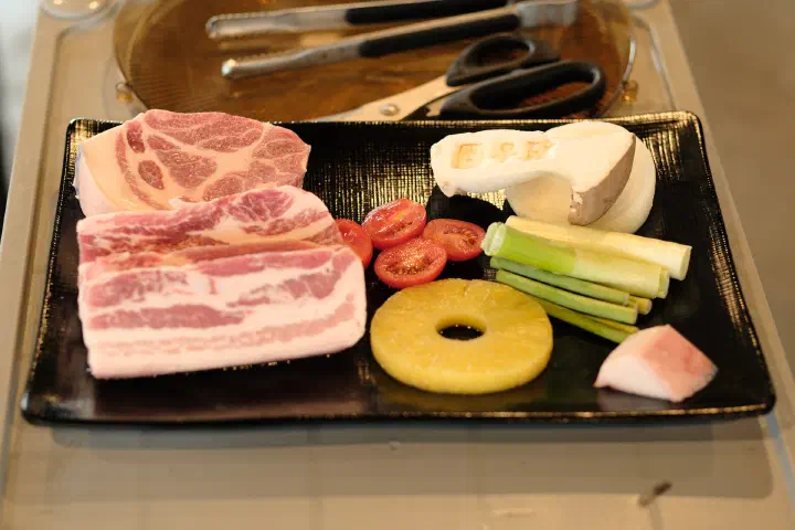 Jeju black pork served with pineapple, cherry tomato, green onion, onion, and mushroom for the grill
