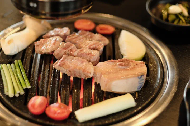 Bite-sized pieces of Jeju black pork neck finishing on the charcoal grill